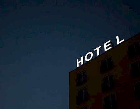 The image shows a building with an illuminated sign that reads "HOTEL" at night.