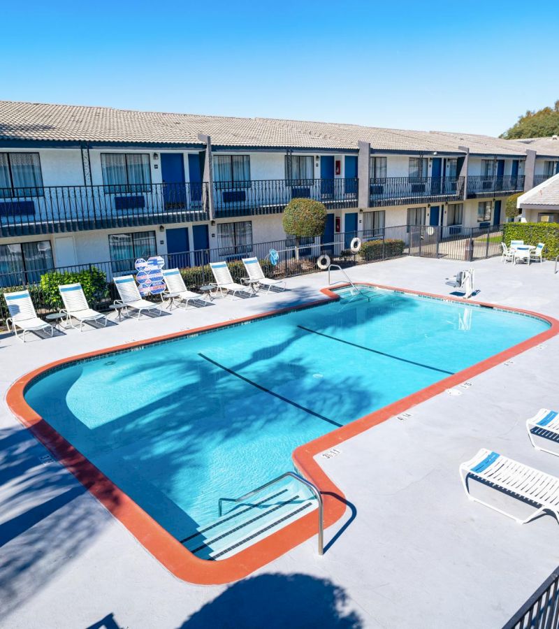A hotel pool with lounge chairs and a building in the background.