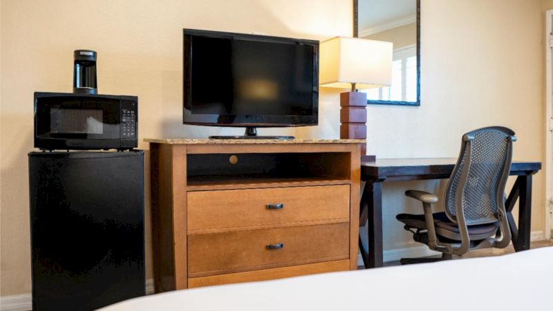 A hotel room with a bed, desk, TV, mini-fridge, and microwave