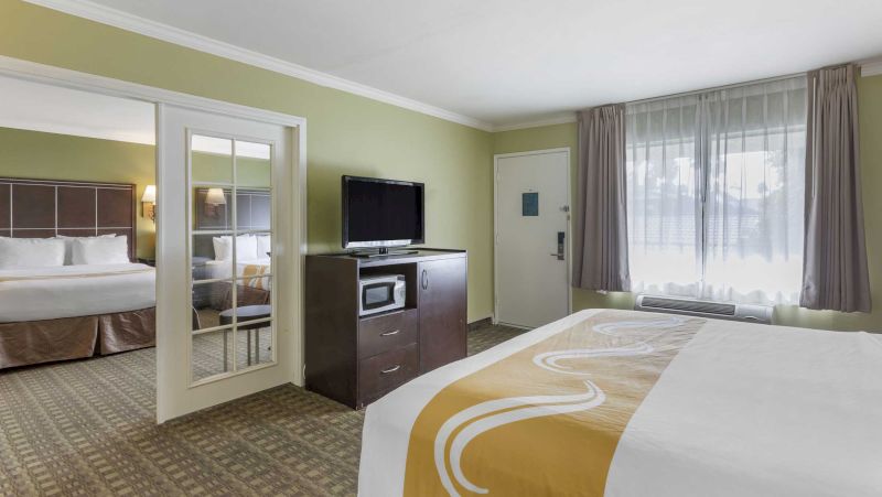 A hotel room with two beds, a TV, microwave, and window