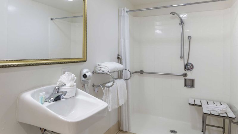 A clean bathroom with a sink, shower, and mirror