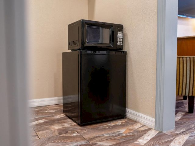A mini fridge and microwave on a tiled floor in a room.