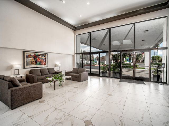 A hotel lobby with a seating area, large windows, and a tiled floor.
