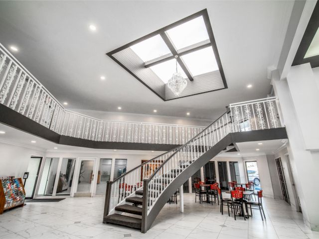 A large, open lobby with a staircase, skylight, and dining area.