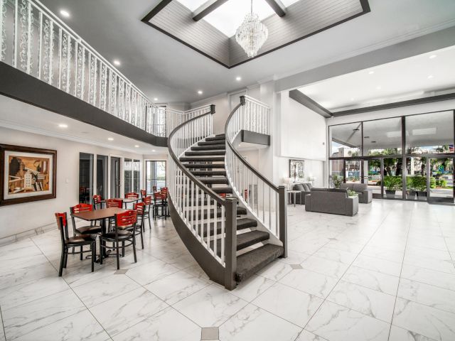 A large, open lobby with a spiral staircase, chandelier, and seating area.