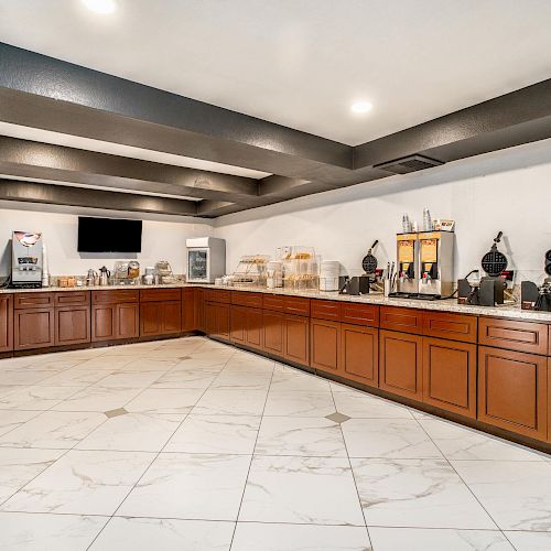 A modern buffet area with various appliances for self-serve breakfast, including coffee machines, waffle makers, and a selection of food items.